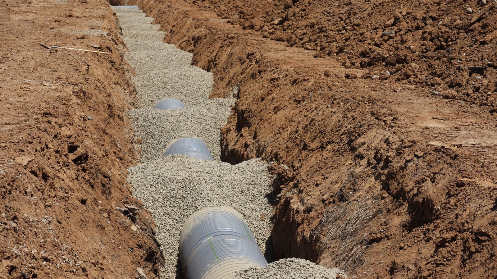 Plastic drainage pipe bedded in gravel in an open trench