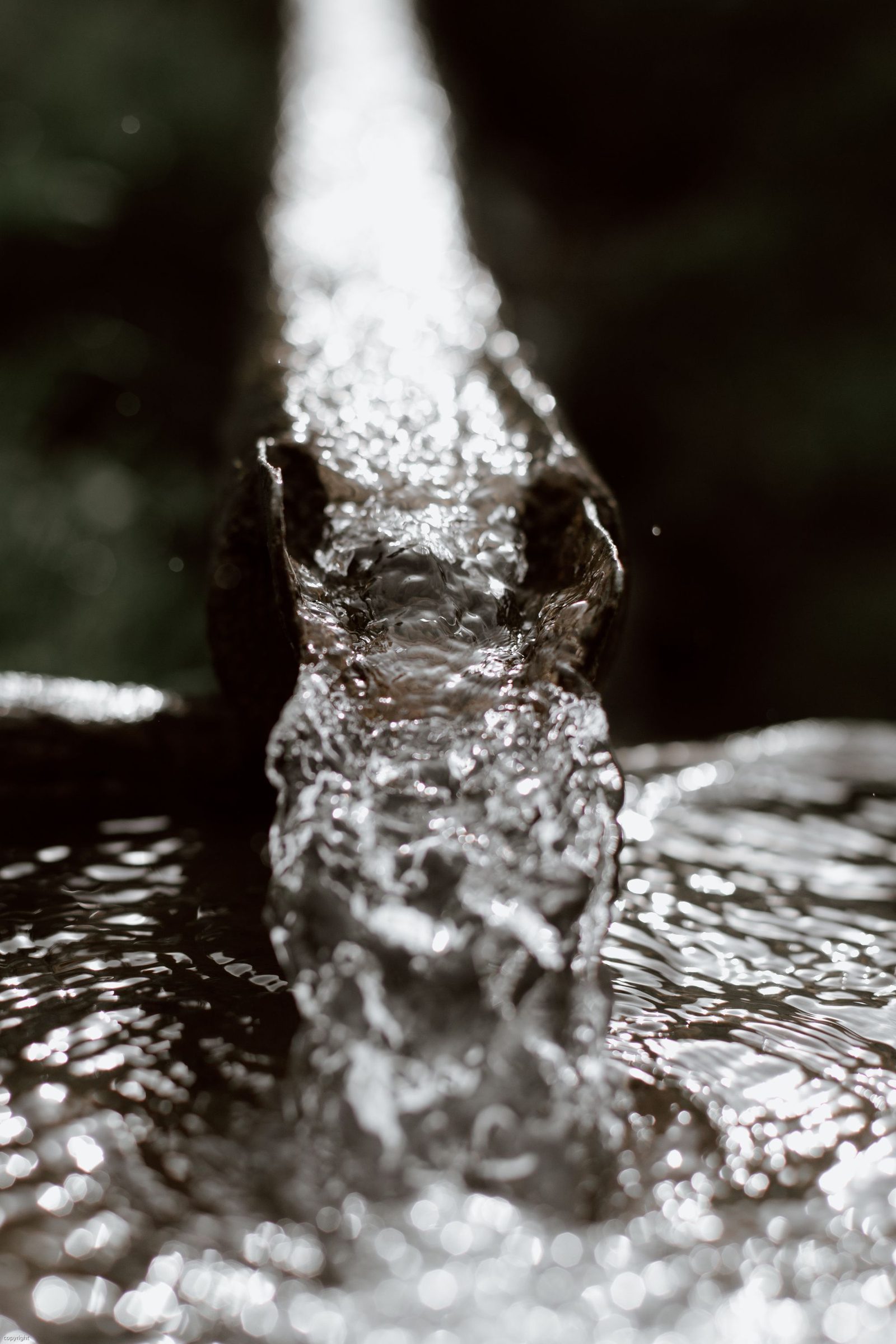 Close-up of water pouring at pressure from a metal outlet