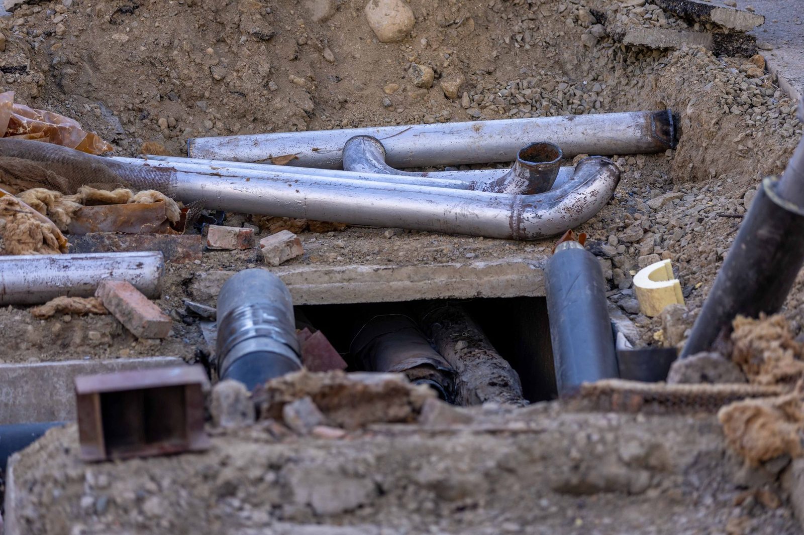 Pipework exposed in an open excavation beside a chamber